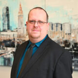 a man in a suit and tie standing in front of a painting
