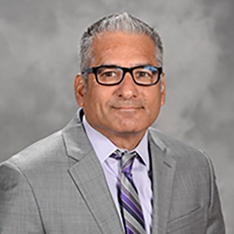 a man in a suit and tie standing in front of a gray background