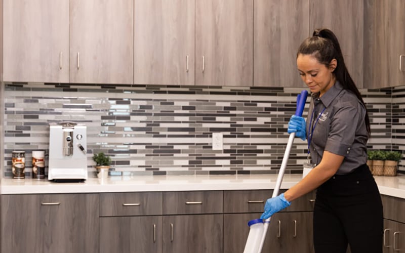 a woman cleaning a kitchen counter with a mop