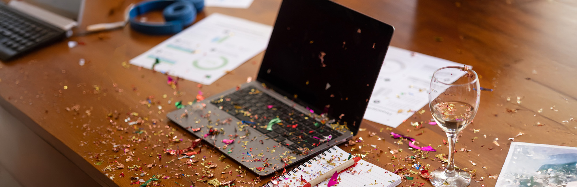 laptop on desk with confetti left over from a party