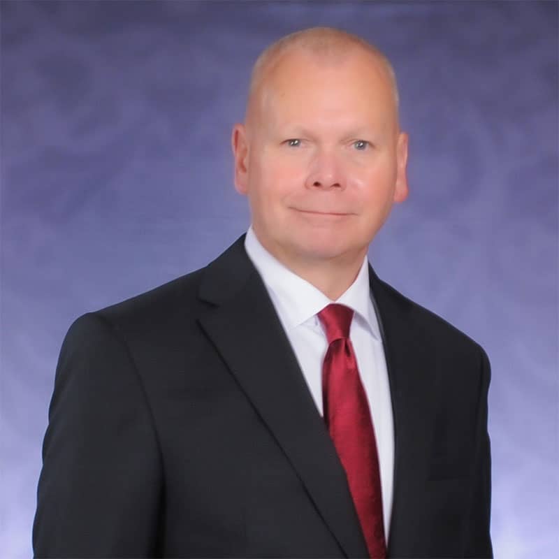 a man in a suit and tie standing next to a blue wall