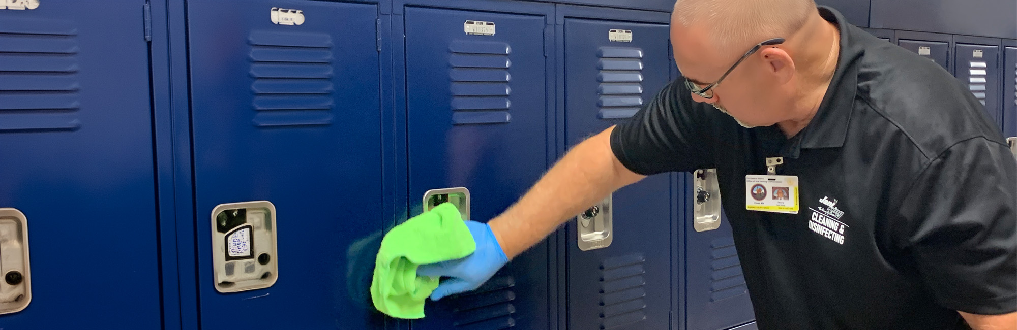 Janitor cleaning school lockers by wiping them down