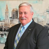 a man in a suit and tie standing in front of a painting