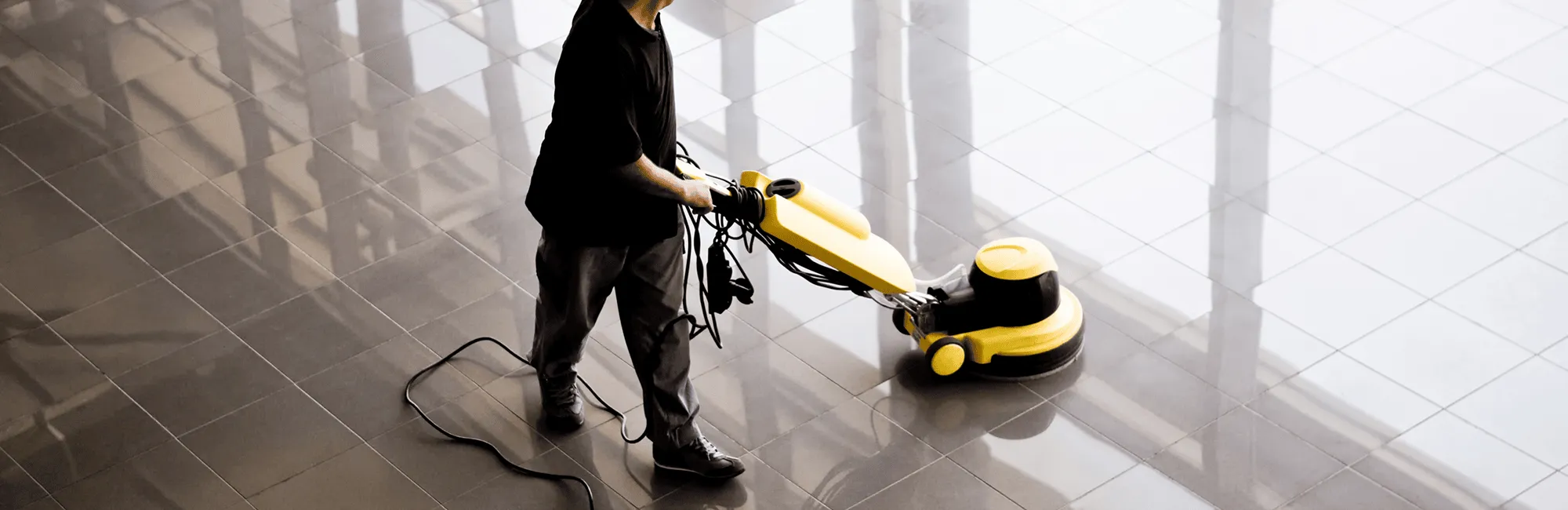 A cleaning employee buffing a hard floor